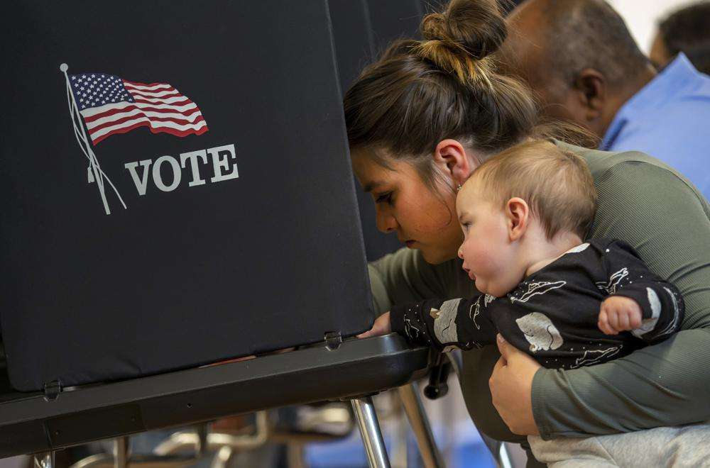 Miranda Padilla holds her 11-month-old son Grayson Sanchez while marking her ballot at a polling center in the South Valley area of Albuquerque, N.M., Tuesday.