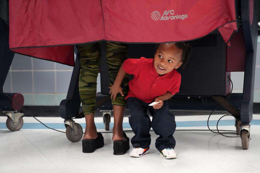 Kash Strong, 3, peeks out from under the curtain of a voting booth as his mother Sophia Amacker casts her vote on Election Day at the Martin Luther King Elementary School in the Lower Ninth Ward of New Orleans, Tuesday.