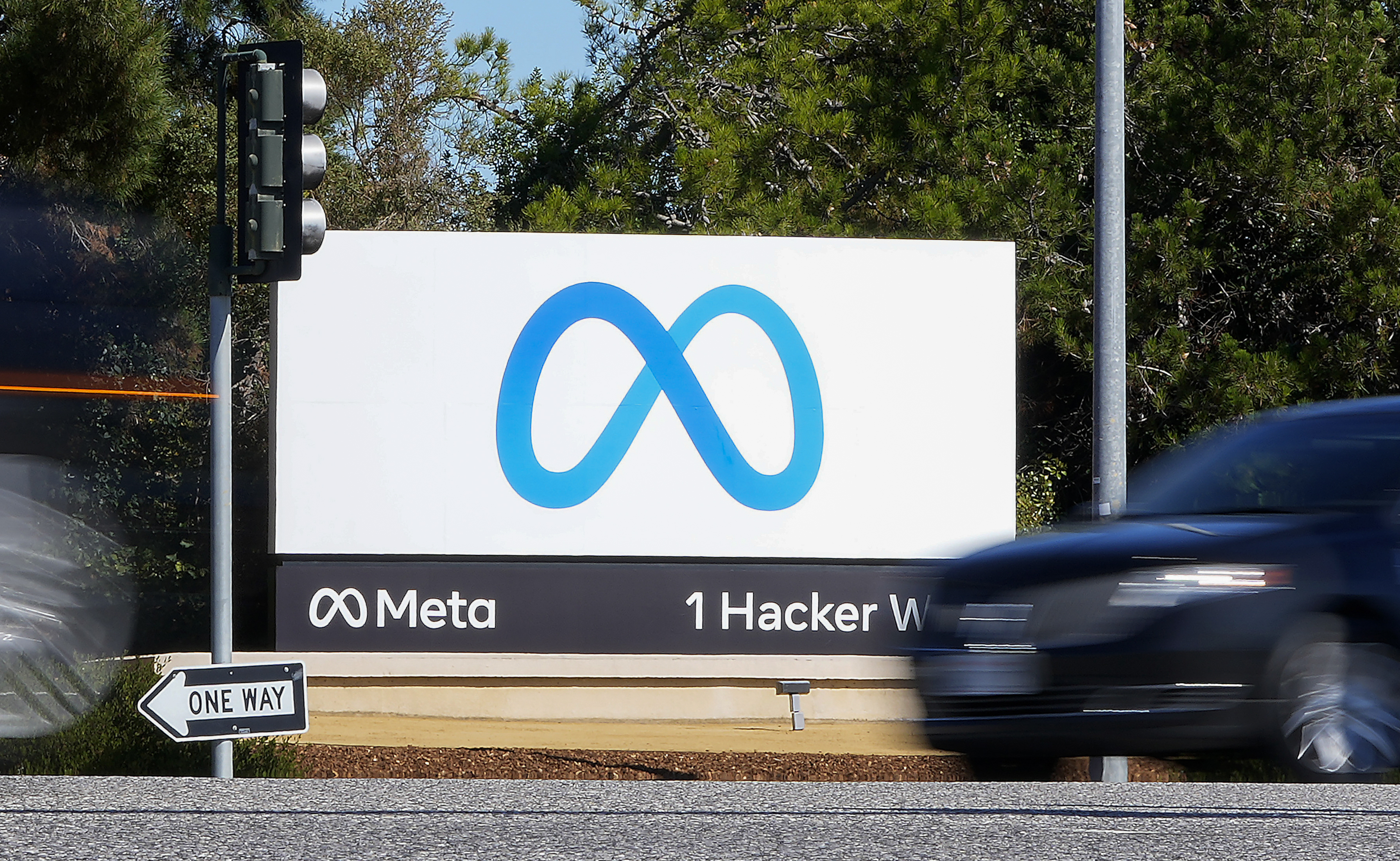 A car passes Facebook's new Meta logo on a sign at the company headquarters on Oct. 28, 2021, in Menlo Park, Calif. Facebook parent Meta is laying off 13% of its employees as it contends with faltering revenue and broader tech industry woes. 