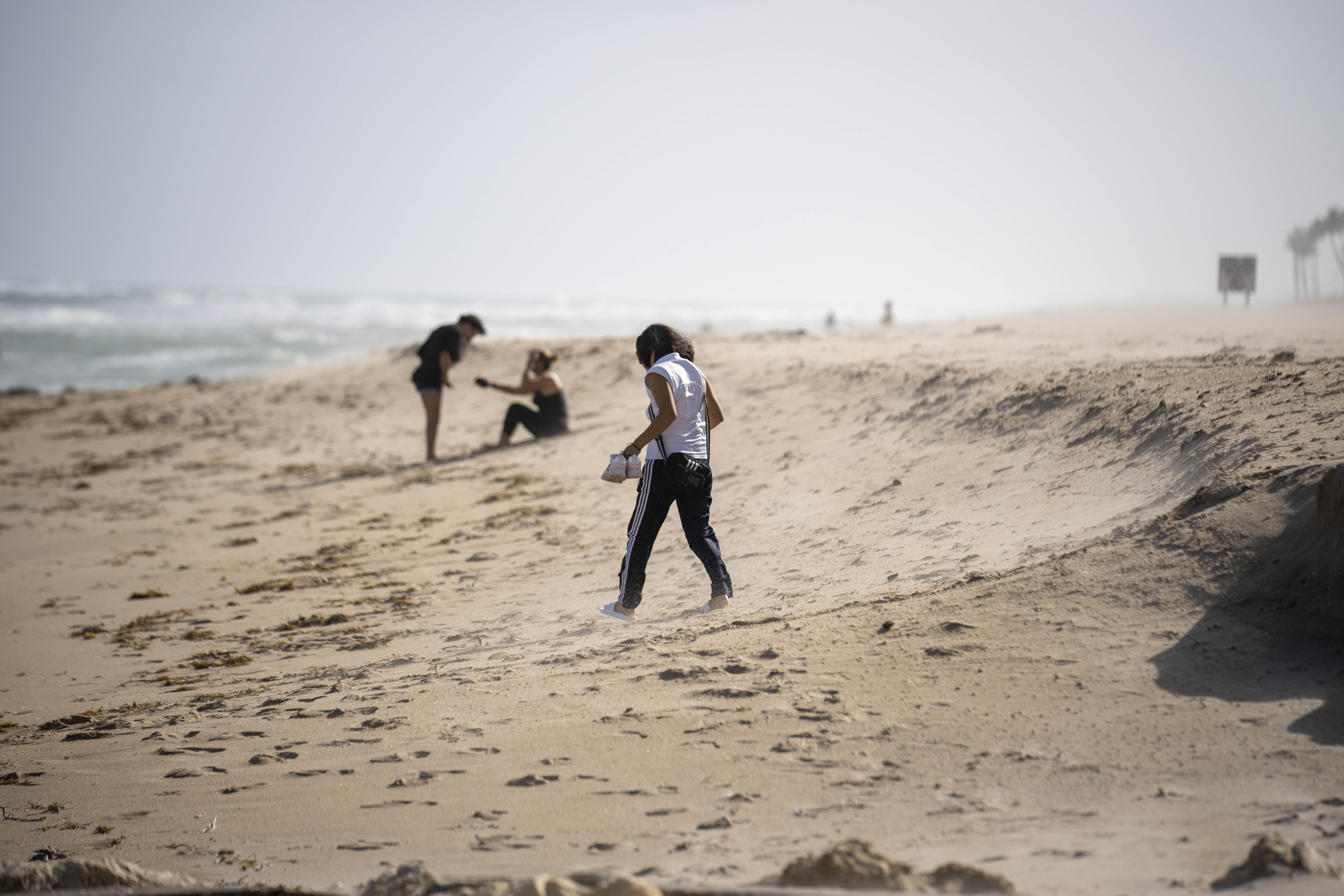 A few people put up with strong wind on the beach in Palm Beach, Fla., Tuesday, as Tropical Storm Nicole continues to increase in strength and is expected to make landfall along Florida's east coast early Thursday.