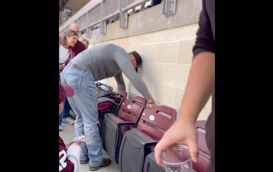 A spectator at Kyle Field in Texas removes an unwanted guest from behind a row of seats on Oct. 29.