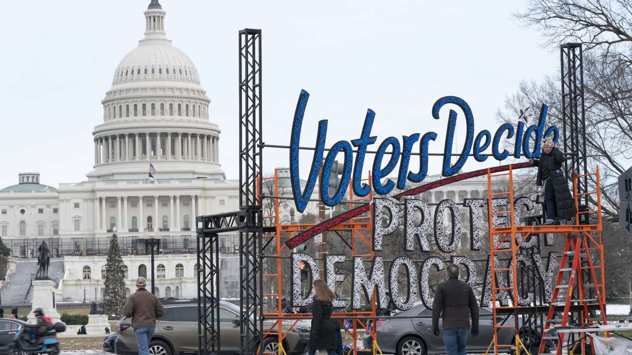 With the U.S. Capitol in the background, people walk past a sign that says say, "Voters Decide Protect Democracy," Jan. 6, in Washington. This week’s ballot had an unspoken candidate, American democracy.