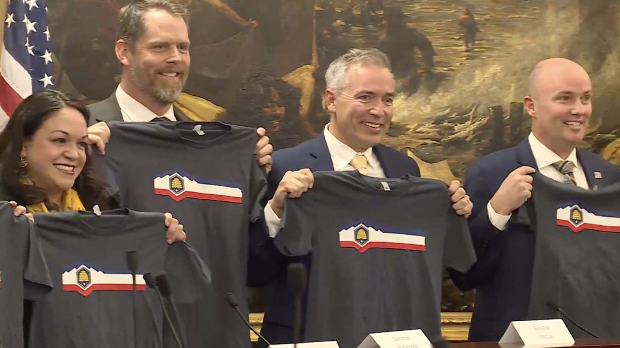 Members of the Utah State Flag Task Force hold T-shirts with a new state flag design after voting to approve the design on Thursday. The Utah Legislature will vote on adopting the state flag design as early as January 2023.
