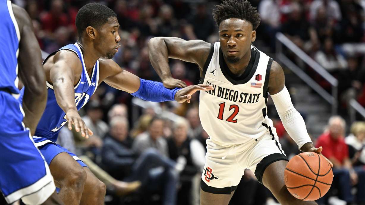 San Diego State guard Darrion Trammell (12) drives past BYU guard Rudi Williams (3) during the first half of an NCAA college basketball game Friday, Nov. 11, 2022, in San Diego.