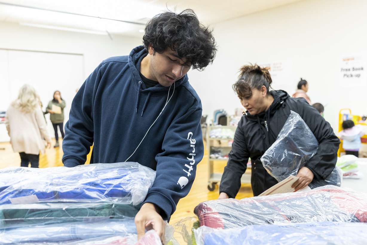 Victor Lopez, left, and his mother Hilda sort though coats being given out by Operation Warm inside the Salt Lake County Library in South Salt Lake on Saturday. The family said they were so “grateful.”