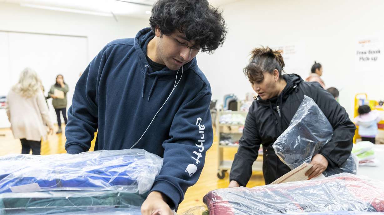 Victor Lopez, left, and his mother Hilda sort though coats being given out by Operation Warm inside the Salt Lake County Library in South Salt Lake on Saturday. The family said they were so “grateful.”