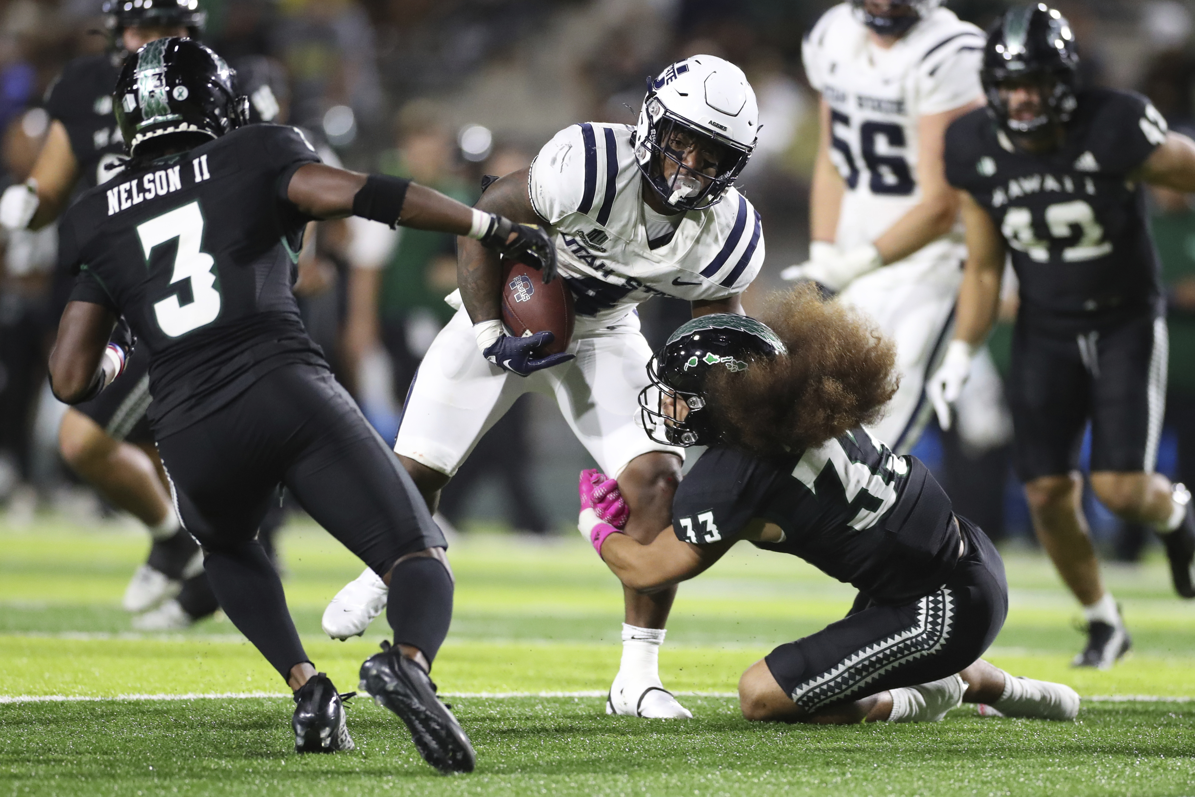 Utah State running back Calvin Tyler Jr. (4) gets past Hawaii defensive back Peter Manuma (33) during the second quarter of an NCAA college football game Saturday, Nov. 12, in Honolulu.