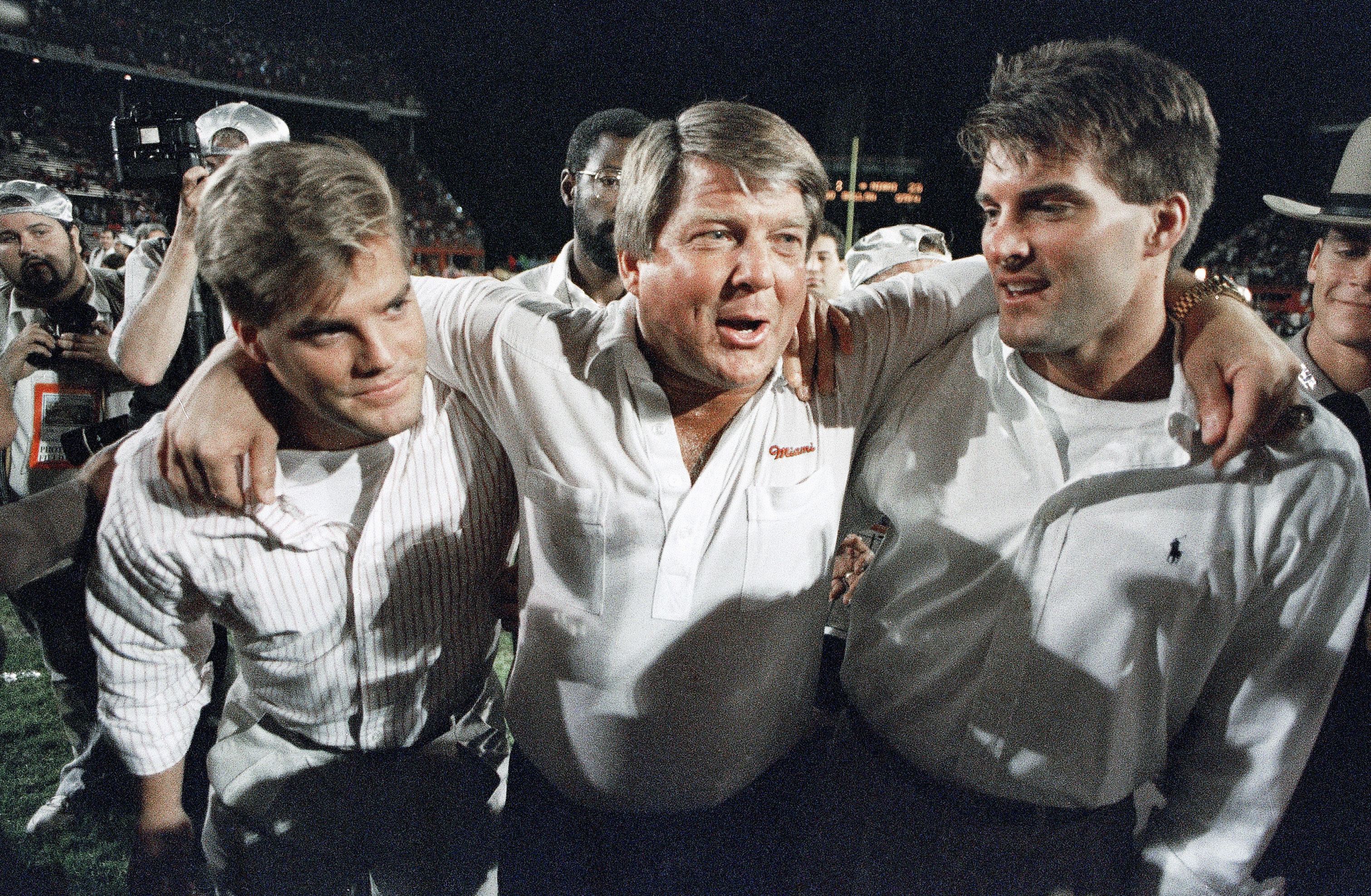 FILE - Miami coach Jimmy Johnson, center, is hugged by his sons, Chad, left, and Brent, rightk, while walking off the field following the team's win over Nebraska in the Orange Bowl college football game in Miami, Jan. 2, 1989. Johnson won two Super Bowls as coach of the Dallas Cowboys and a national championship at Miami. In his view, Johnson’s biggest success has nothing to do with football. The 79-year-old Johnson describes in “Swagger,” his memoir that released on Tuesday, how his addiction to football and winning caused him to never have a family dinner. His two sons played football but Dad never saw them play a full game.  