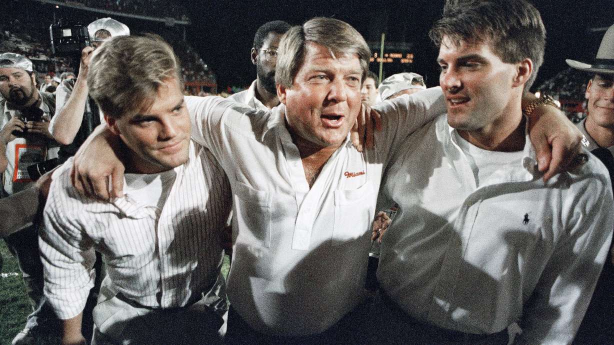 FILE - Miami coach Jimmy Johnson, center, is hugged by his sons, Chad, left, and Brent, rightk, while walking off the field following the team's win over Nebraska in the Orange Bowl college football game in Miami, Jan. 2, 1989. Johnson won two Super Bowls as coach of the Dallas Cowboys and a national championship at Miami. In his view, Johnson’s biggest success has nothing to do with football. The 79-year-old Johnson describes in “Swagger,” his memoir that released on Tuesday, how his addiction to football and winning caused him to never have a family dinner. His two sons played football but Dad never saw them play a full game.