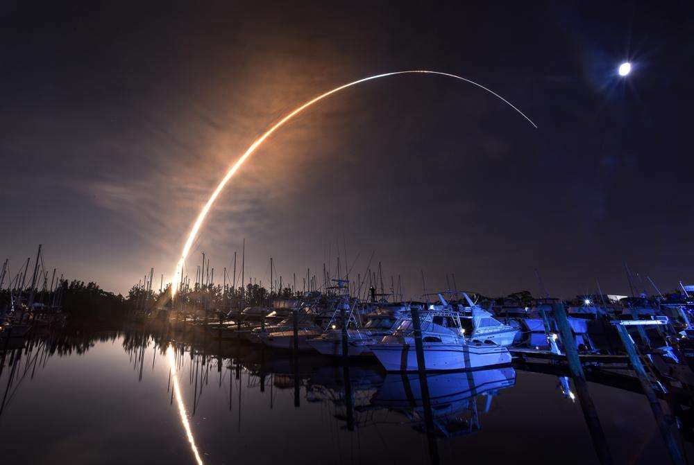 NASA's new moon rocket lifts off from the Kennedy Space Center in Cape Canaveral, Wednesday morning, as seen from Harbor town Marina on Merritt Island, Fla. The moon is visible in the sky.