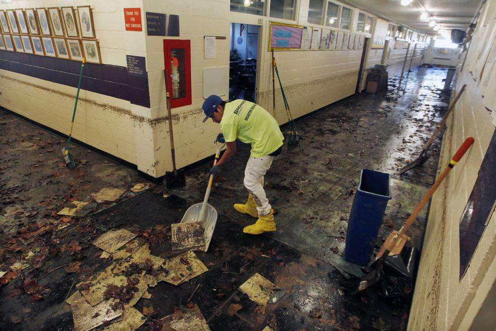 A worker scrapes up mud and tiles from flood-damaged Saint Rose High School in Belmar, N.J., on Nov. 4, 2012, after storm surge caused by Superstorm Sandy. Ninety percent of counties in the United States experienced a weather-related disaster between 2011-2021, according to a report published on Wednesday. Over 300 million people — 93% of the country’s population — live in those counties.