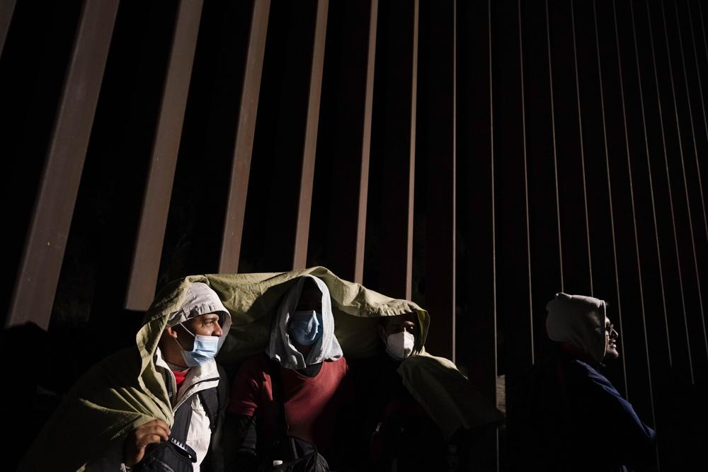 Four men from Cuba try to keep warm after crossing the border from Mexico and surrendering to authorities to apply for asylum on Nov. 3 near Yuma, Ariz. U.S. District Judge Emmet Sullivan on Tuesday ordered the Biden administration to lift Trump-era asylum restrictions that have been a cornerstone of border enforcement since the beginning of COVID-19.