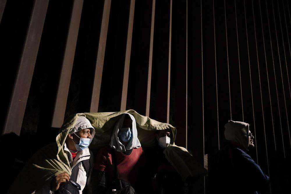 Four men from Cuba try to keep warm after crossing the border from Mexico and surrendering to authorities to apply for asylum on Nov. 3 near Yuma, Ariz. U.S. District Judge Emmet Sullivan on Tuesday ordered the Biden administration to lift Trump-era asylum restrictions that have been a cornerstone of border enforcement since the beginning of COVID-19.