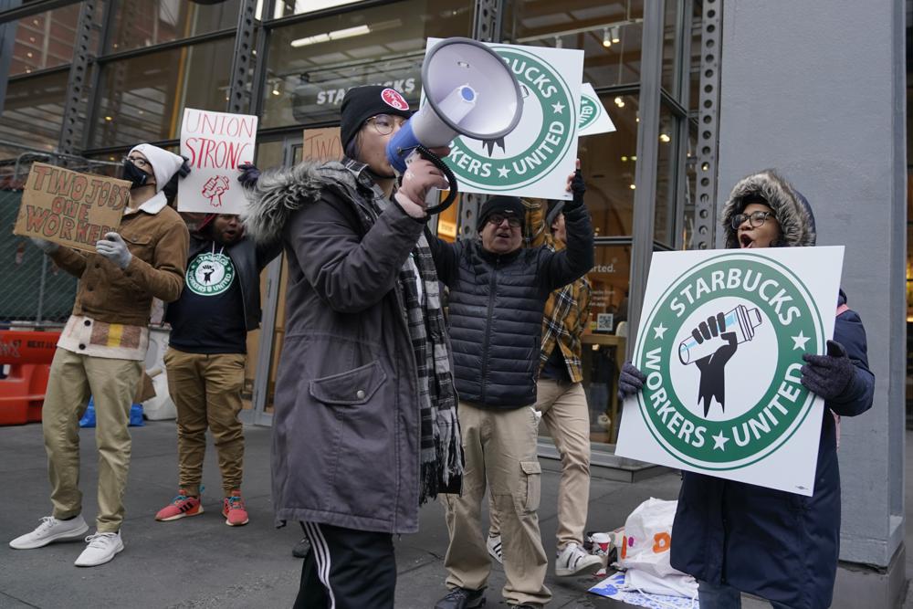 People chant and hold signs in front of a Starbucks in New York, Thursday. Starbucks workers at more than 100 U.S. stores say they're going on strike Thursday in what would be the largest labor action since a campaign to unionize the company's stores began late last year.
