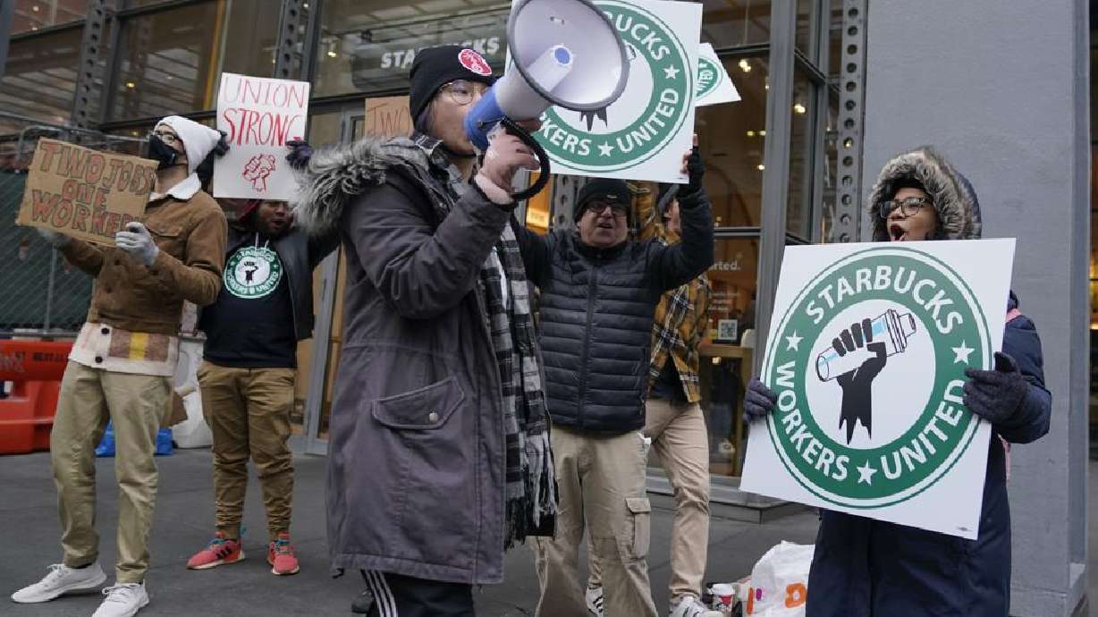 People chant and hold signs in front of a Starbucks in New York, Thursday. Starbucks workers at more than 100 U.S. stores say they're going on strike Thursday in what would be the largest labor action since a campaign to unionize the company's stores began late last year.