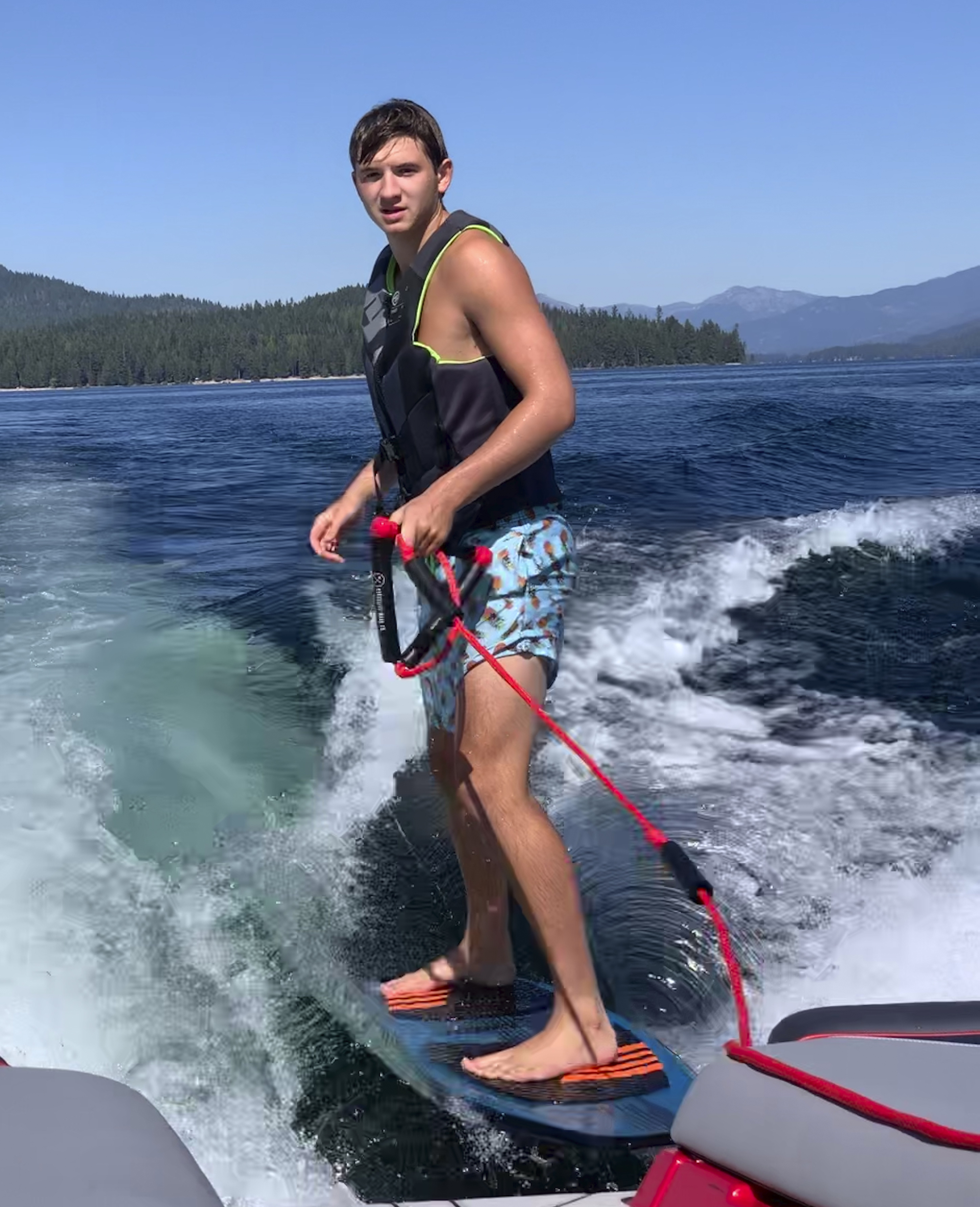 In this photo provided by Stacy Chapin, Ethan Chapin surfs on Priest Lake in northern Idaho in this family snapshot from July. Chapin was one of four University of Idaho students found stabbed to death in a home near the Moscow, Idaho campus on Sunday.