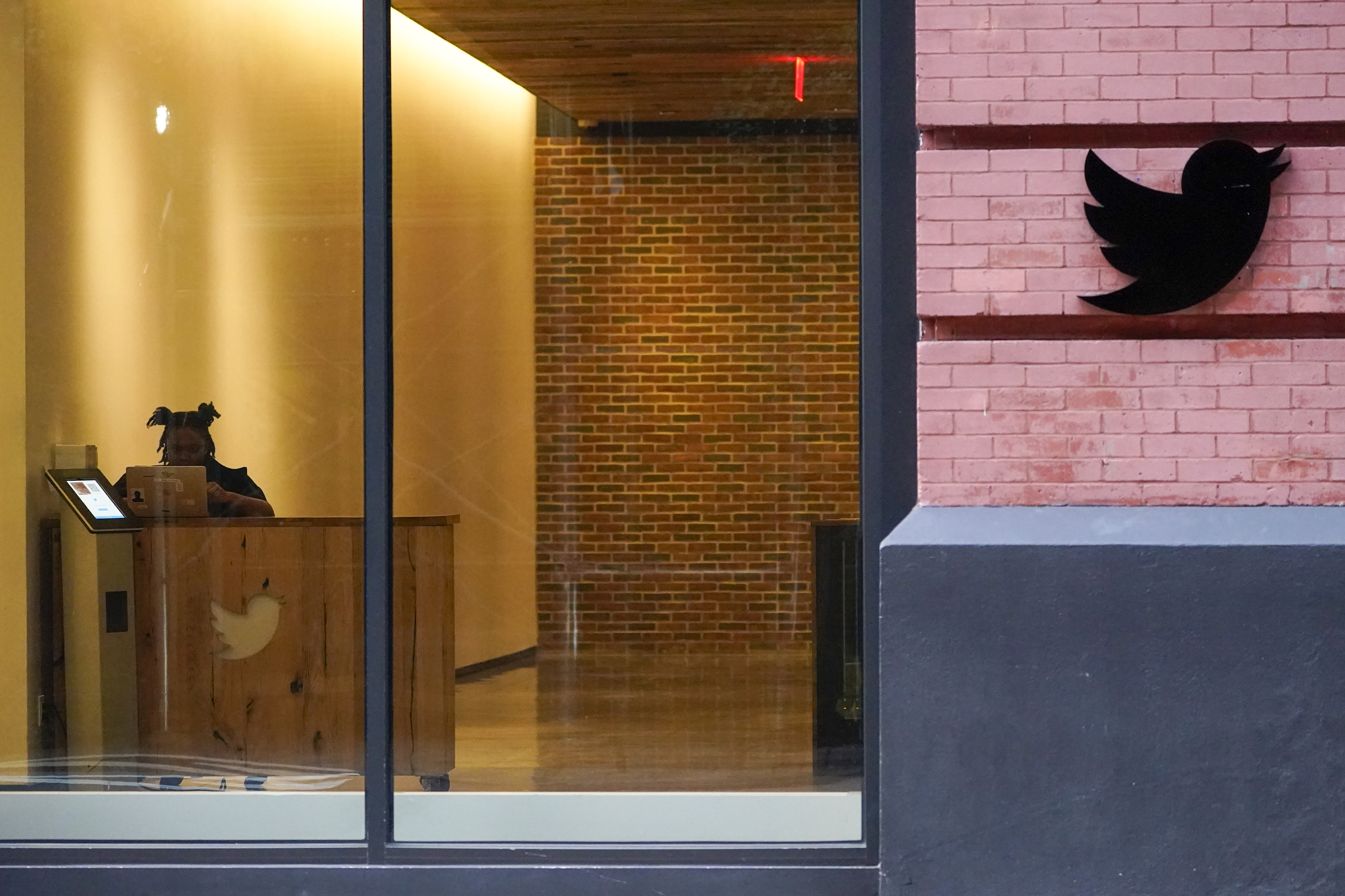 A receptionist works in the lobby of the building that houses the Twitter office in New York, Oct. 26. On Thursday,Twitter continued to bleed engineers and other workers after new owner Elon Musk gave them a choice to pledge to “hardcore” work or resign with severance pay. 