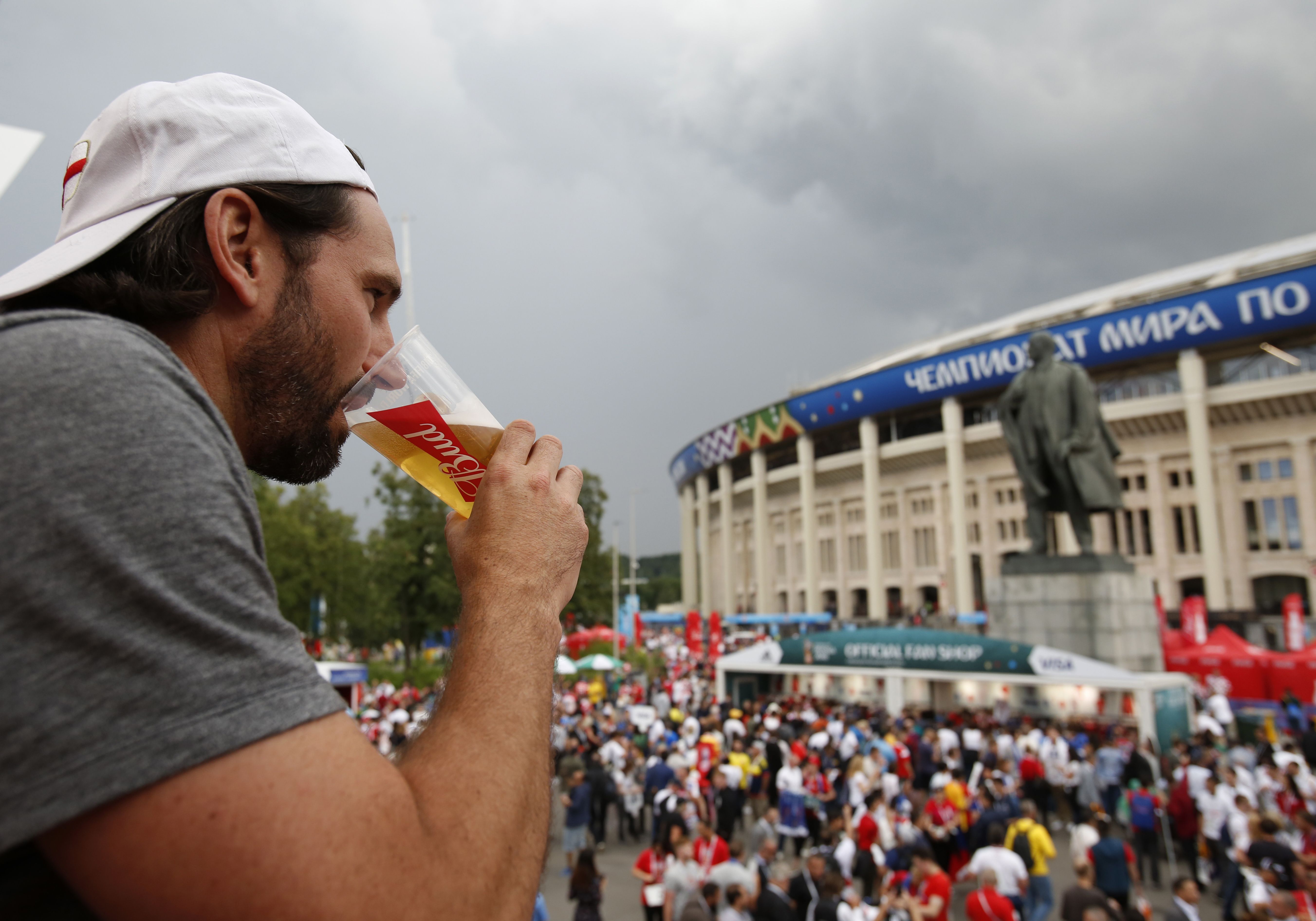 In this July 11, 2018, photo, a man drinks a beer in a Budweiser pavilion in front of the Lenin statue and the Luzhniki Stadium as fans arrive for the semifinal match between Croatia and England, during the 2018 soccer World Cup in Moscow, Russia. The sale of all beer with alcohol at the eight World Cup stadiums in Qatar has been banned. 