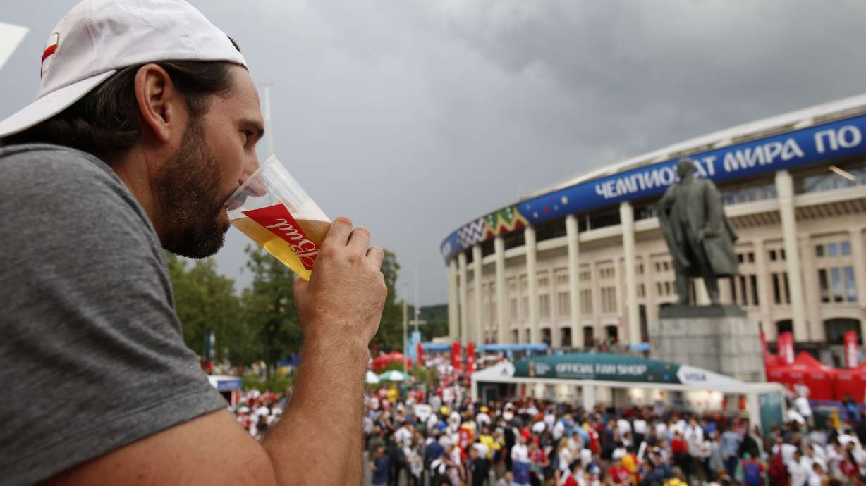 In this July 11, 2018, photo, a man drinks a beer in a Budweiser pavilion in front of the Lenin statue and the Luzhniki Stadium as fans arrive for the semifinal match between Croatia and England, during the 2018 soccer World Cup in Moscow, Russia. The sale of all beer with alcohol at the eight World Cup stadiums in Qatar has been banned.