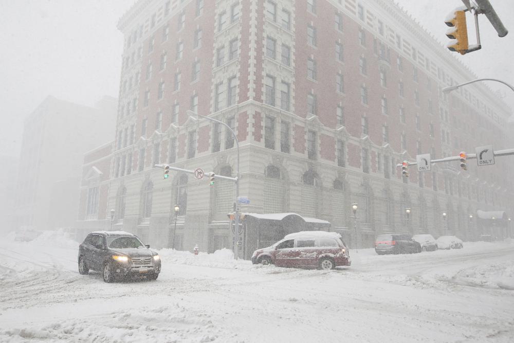 Cars drive along Ellicott Street as snow falls Friday in Buffalo, N.Y. A dangerous lake-effect snowstorm paralyzed parts of western and northern New York, with nearly two feet of snow already on the ground in some places and possibly much more on the way.