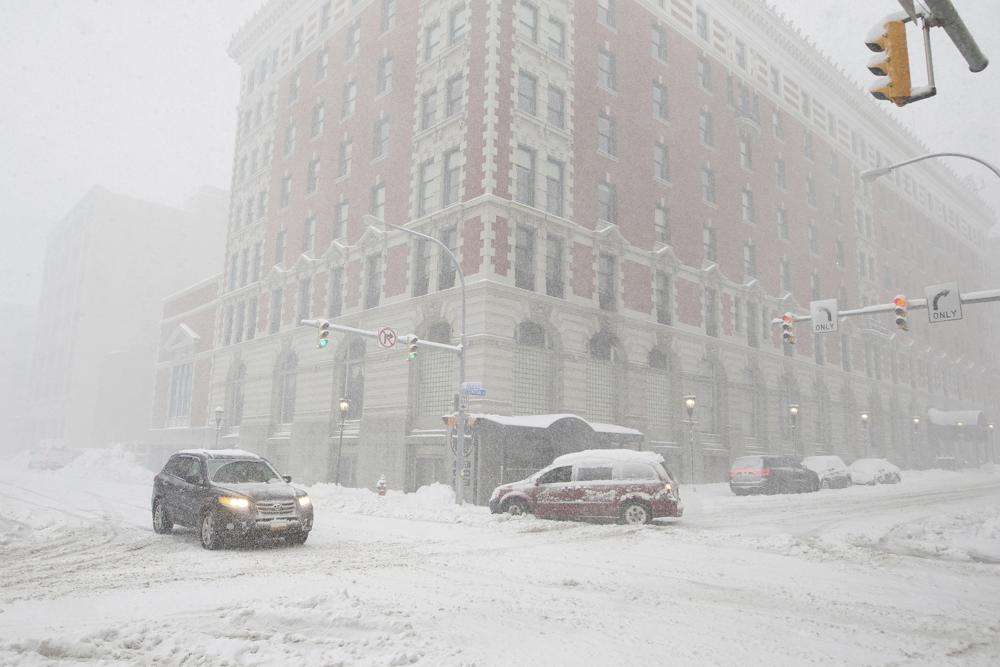 Cars drive along Ellicott Street as snow falls Friday in Buffalo, N.Y. A dangerous lake-effect snowstorm paralyzed parts of western and northern New York, with nearly two feet of snow already on the ground in some places and possibly much more on the way.