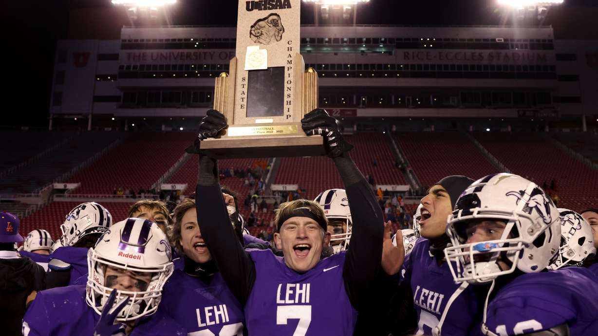 Lehi ’s Jace John (7) hoists up the team’s trophy after beating Timpview in overtime by a score of 29-23 in the 5A state championship game at Rice-Eccles Stadium in Salt Lake City on Friday, Nov. 18, 2022.