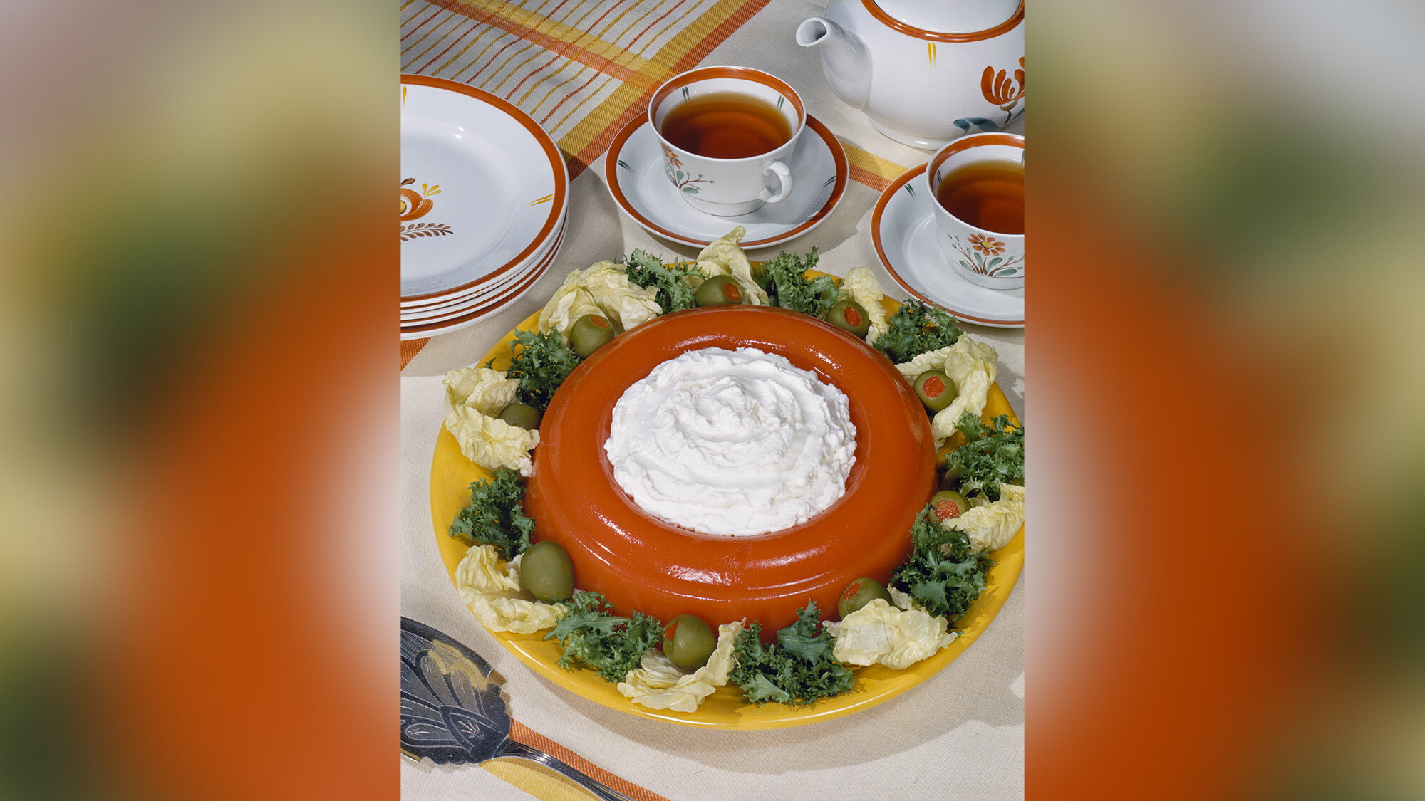 A Jell-O salad with whipped cream, garnished with olives.
