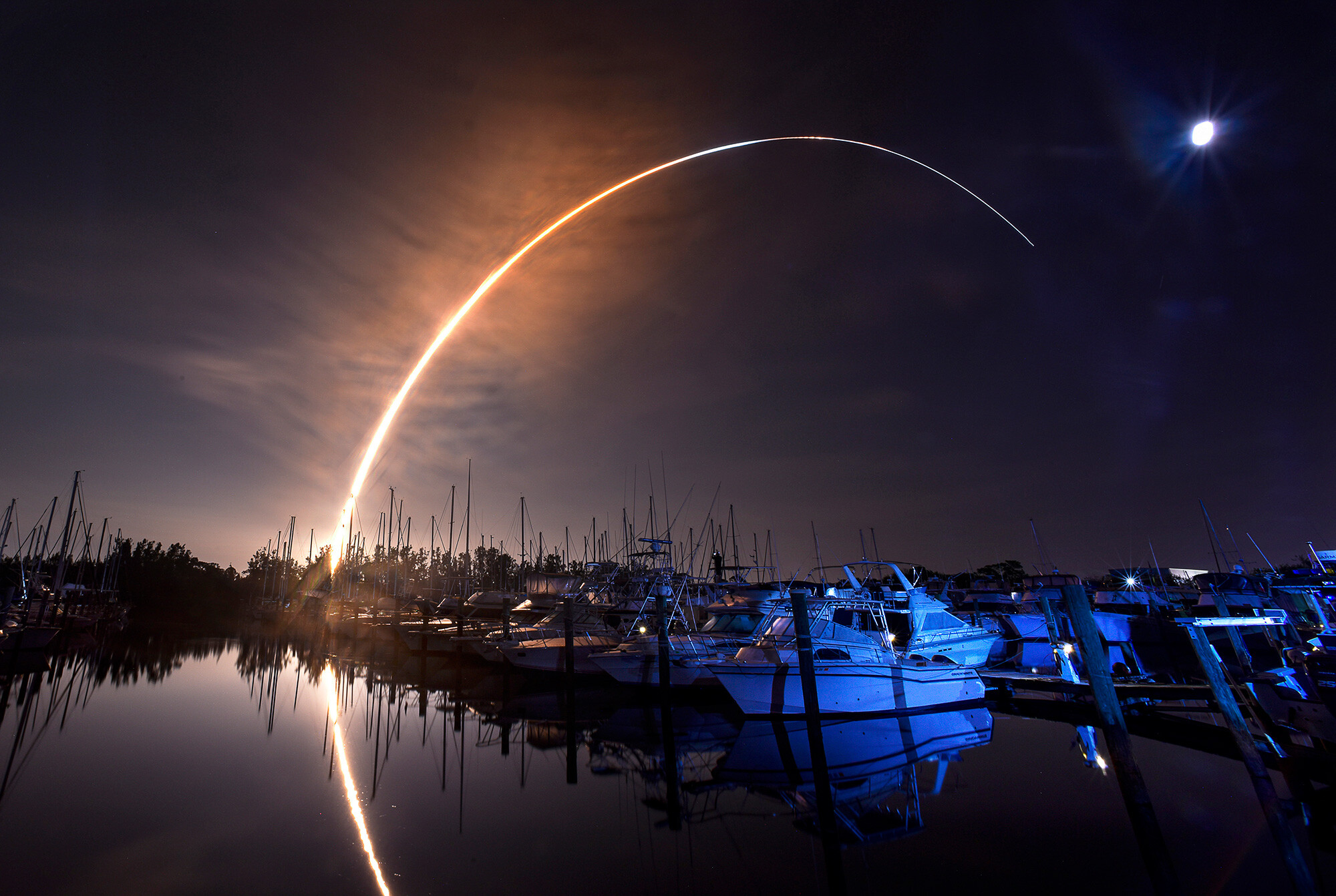 NASA's new moon rocket lifts off from the Kennedy Space Center in Cape Canaveral, Wednesday as seen from Harbor town Marina on Merritt Island, Fla. The moon is visible in the sky.
