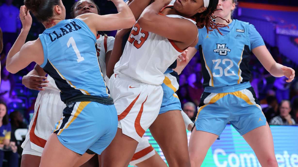 In a photo provided by Bahamas Visual Services, Texas' Aaliyah Moore (23) tries to get possession of the ball next to Marquette's Nia Clark during an NCAA college basketball game at the Battle 4 Atlantis on Saturday, Nov. 19, 2022, at Paradise Island, Bahamas.