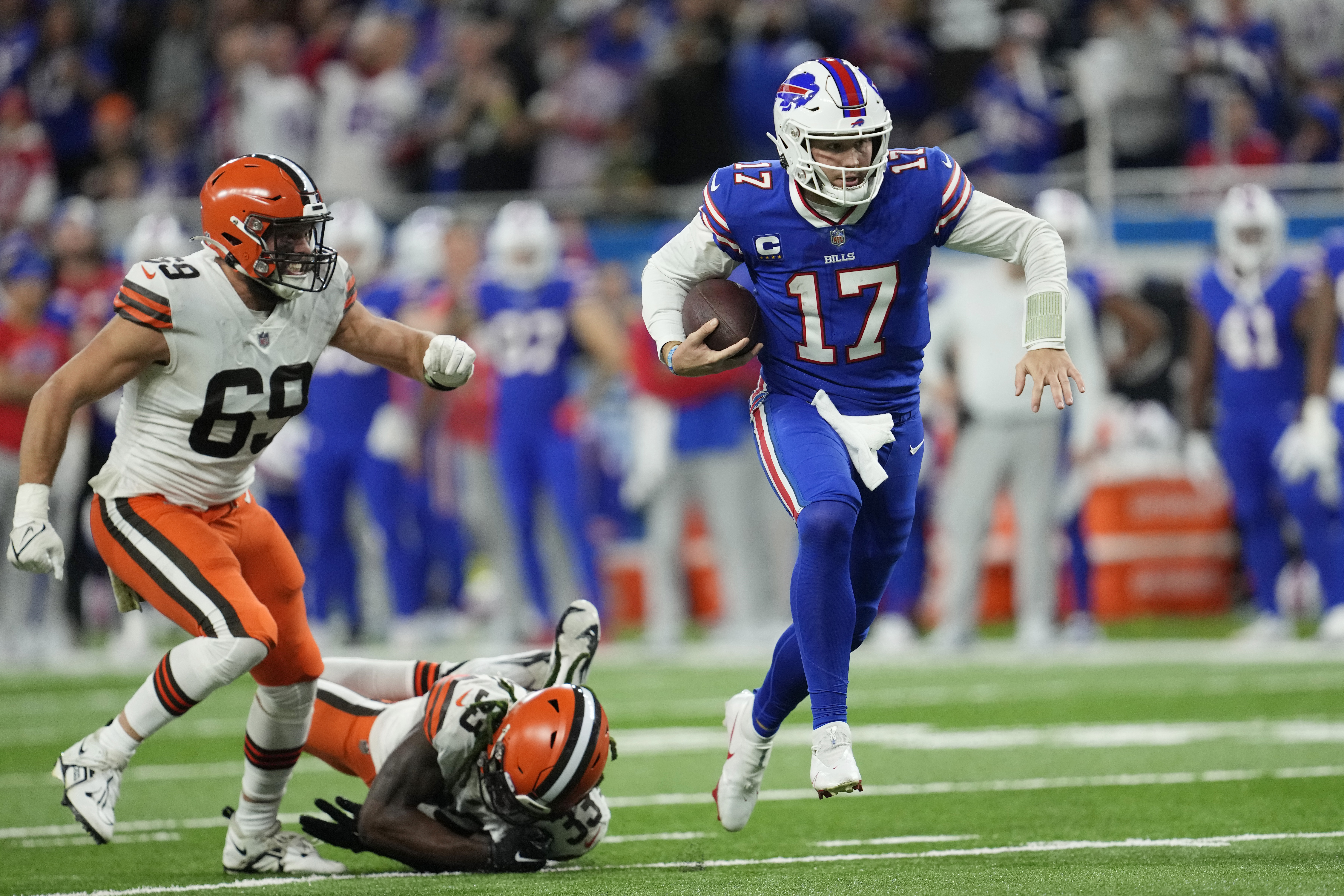 Buffalo Bills quarterback Josh Allen (17) scrambles past Cleveland Browns defensive end Chase Winovich (69) and safety Ronnie Harrison Jr. (33) during the second half of an NFL football game, Sunday, Nov. 20, 2022, in Detroit.