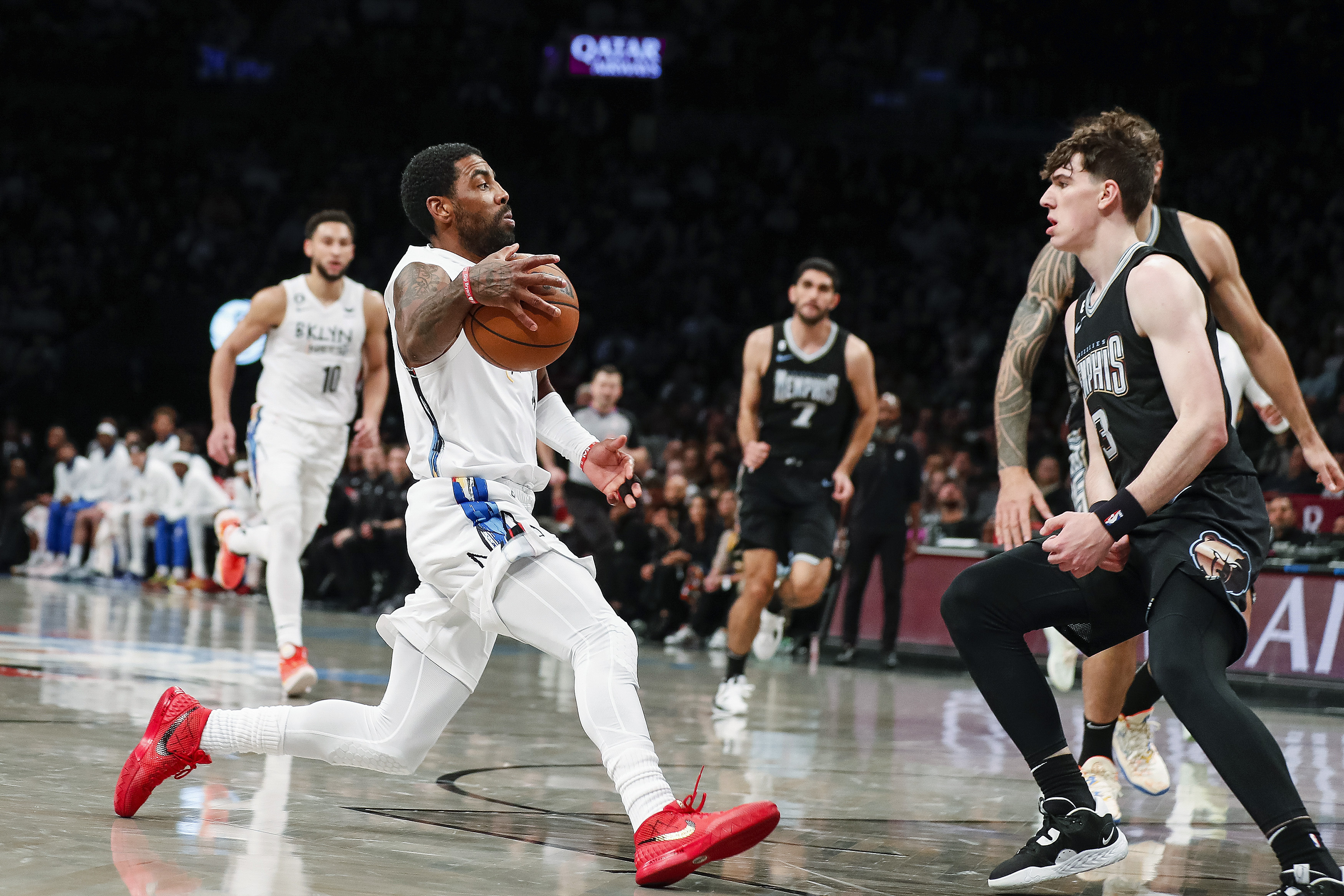 Brooklyn Nets guard Kyrie Irving, left, dribbles against Memphis Grizzlies forward Jake LaRavia (3) during the first half of an NBA basketball game Sunday, Nov. 20, 2022, in New York. 