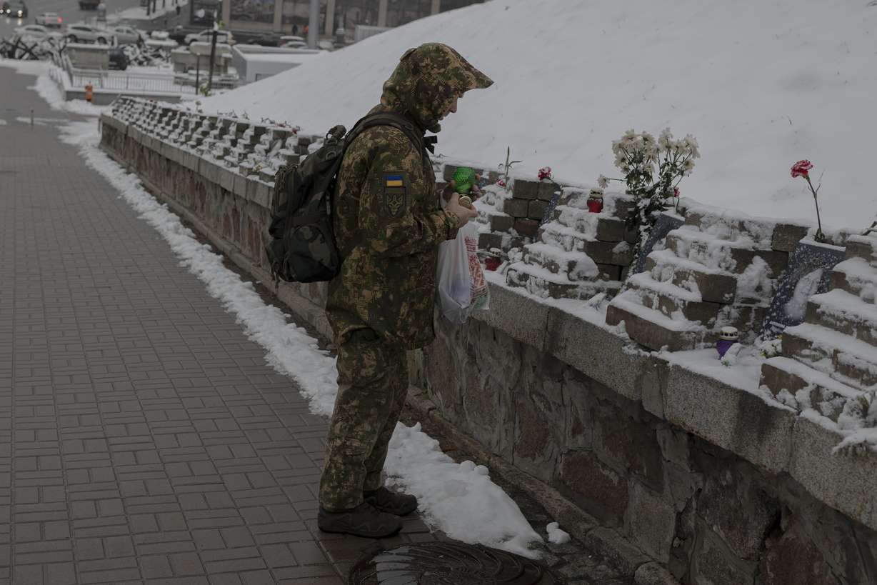 A Ukrainian serviceman lights a candle at a memorial dedicated to people who died in clashes with security forces, at the Independent Square (Maidan) in Kyiv, Ukraine, Monday.