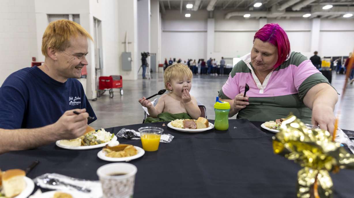Jesse Dumas, left, sits with his son Jesse Jr., 18 months, and his wife, Dawn, as they eat together at the Salt Palace Convention Center where Thanksgiving meals are provided by the Larry H. Miller family in Salt Lake City on Monday.