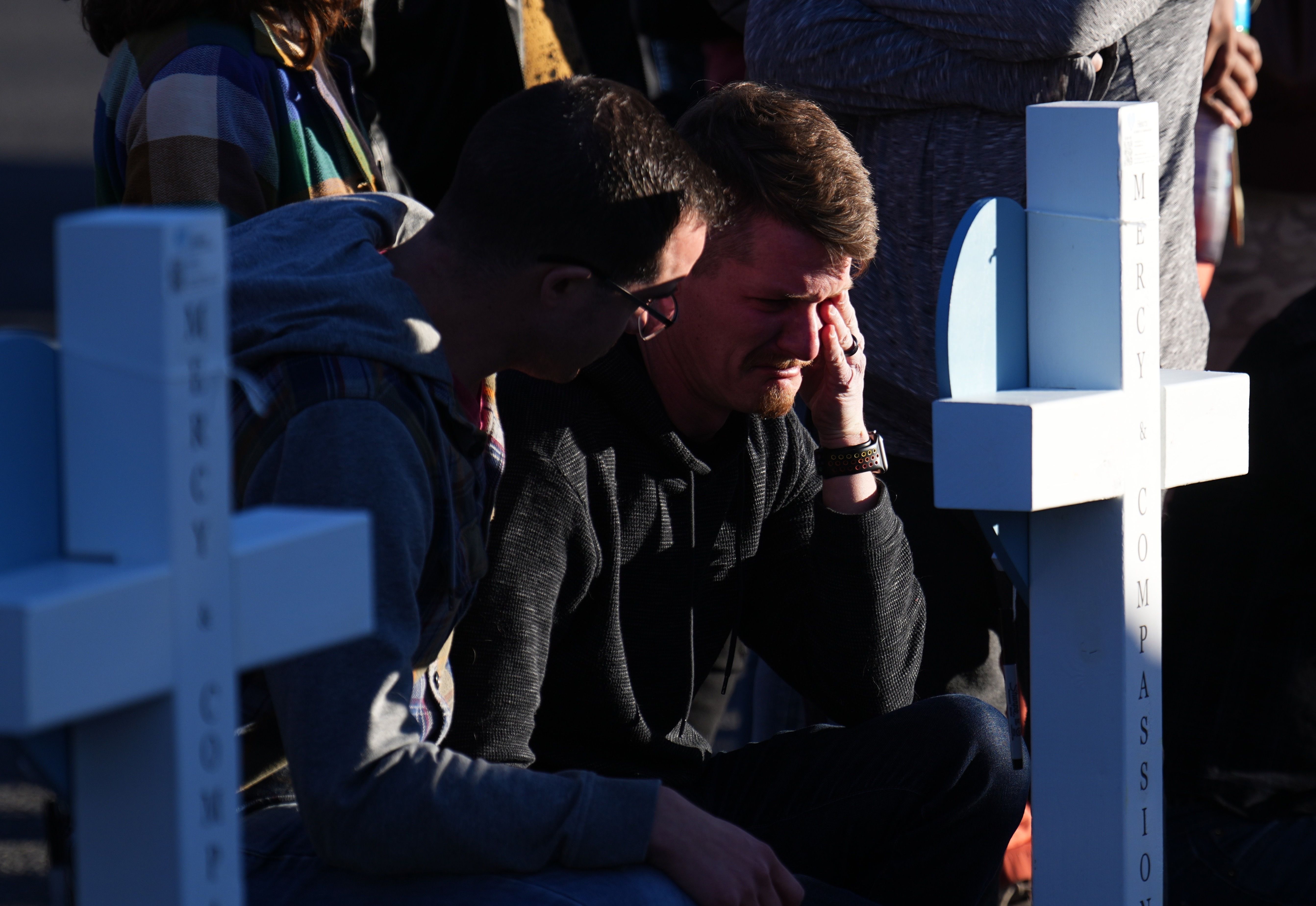 A man cries at a makeshift display of flower bouquets on a corner near the site of a weekend mass shooting at a gay bar, Monday, in Colorado Springs, Colo.