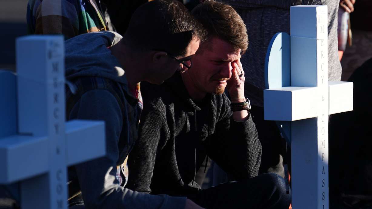 A man cries at a makeshift display of flower bouquets on a corner near the site of a weekend mass shooting at a gay bar, Monday, in Colorado Springs, Colo.