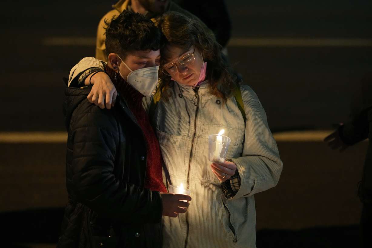 People embrace during a candlelight vigil on a corner near the site of a mass shooting at a gay bar Monday in Colorado Springs, Colo.