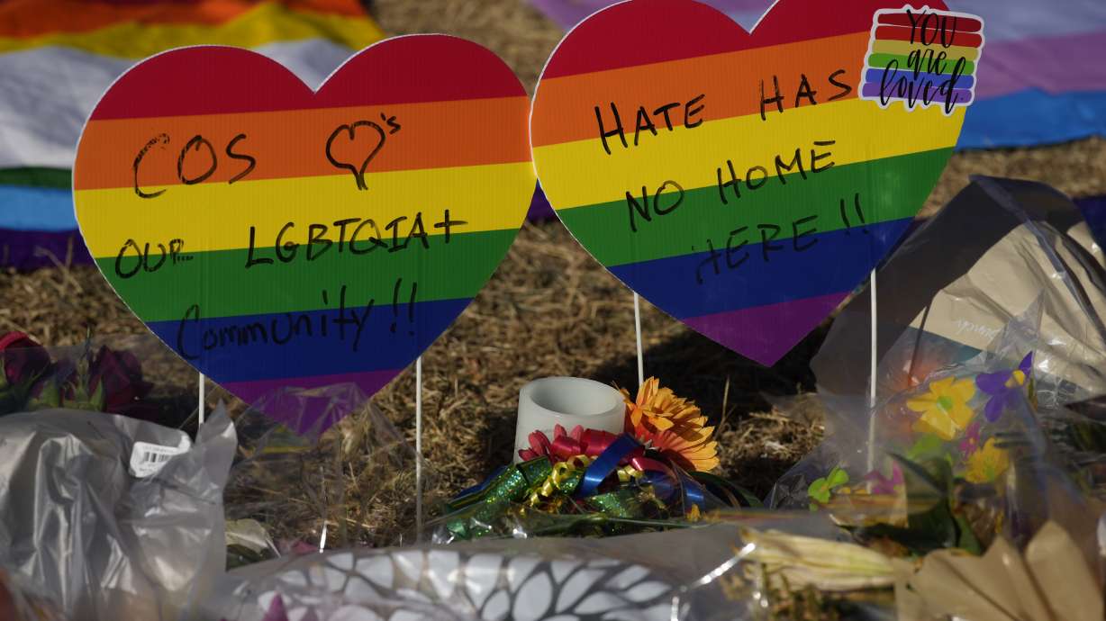 Heart-shaped signs bear messages of support in a makeshift memorial to the victims of a weekend mass shooting at a nearby gay nightclub on Tuesday, in Colorado Springs, Colo. In several standard motions filed on behalf of the suspect, Anderson Lee Aldrich, on Tuesday, public defenders refer to the suspect as "Mx. Aldrich."