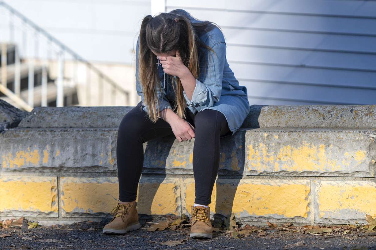 University of Idaho student Alaina Tempelis, of Seattle Wash., prays with a cross in her hand, Thursday, Nov. 17, in Moscow, Idaho, outside of the home where four fellow students were recently murdered. Tempelis said she frequently ate at Mad Greek in downtown where Xana Kernodle and Madison Mogen worked for several years.