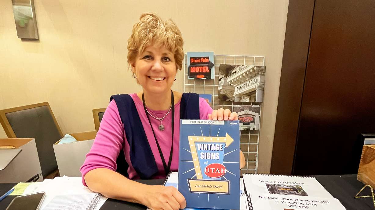 Lisa Michele Church, author of the book "Vintage Signs of Utah," holds up a copy of the book during the Utah State Historical Society Conference on Oct. 26. The book highlights historic Utah signs that are mostly still visible today.
