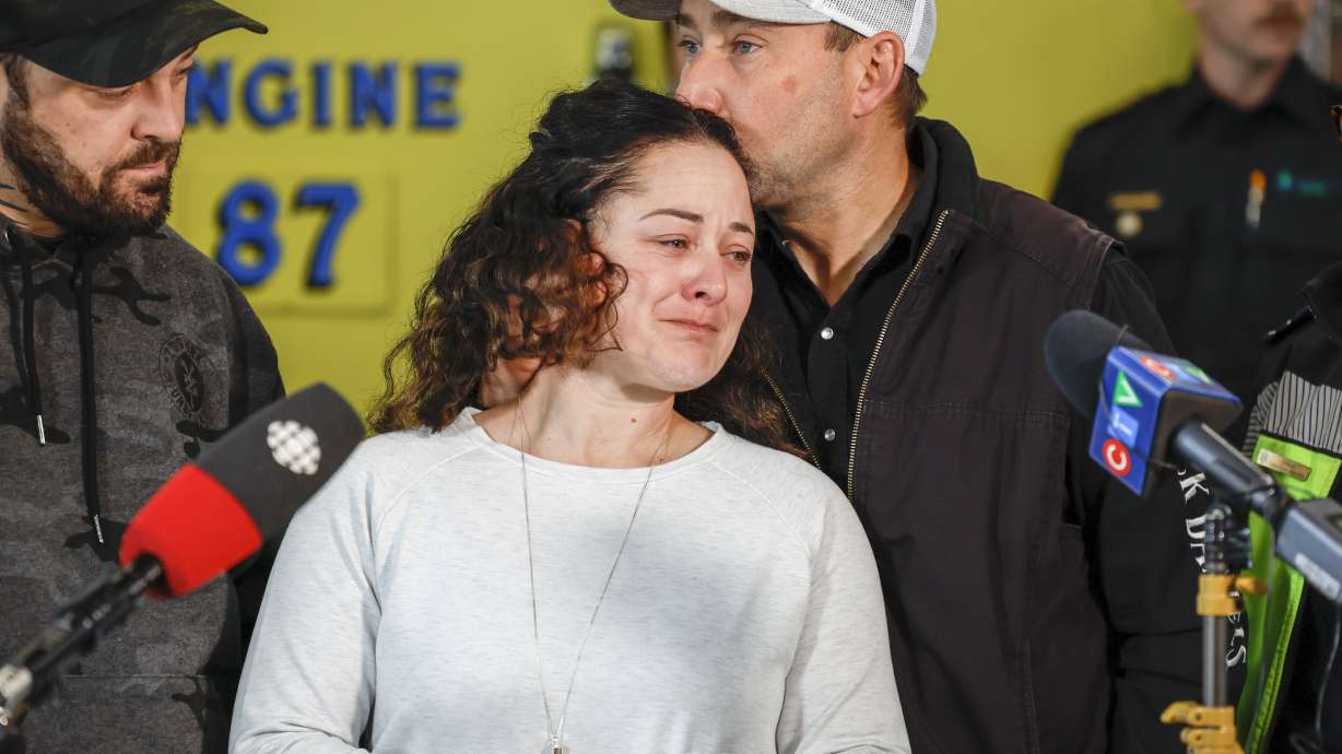 Paramedic Jayme Erickson, center, who was called to a crash last week and didn't know she was trying to save her own daughter because the injuries were too severe, is comforted by her husband Sean Erickson, as she speaks to the media in Airdrie, Alberta, Tuesday.