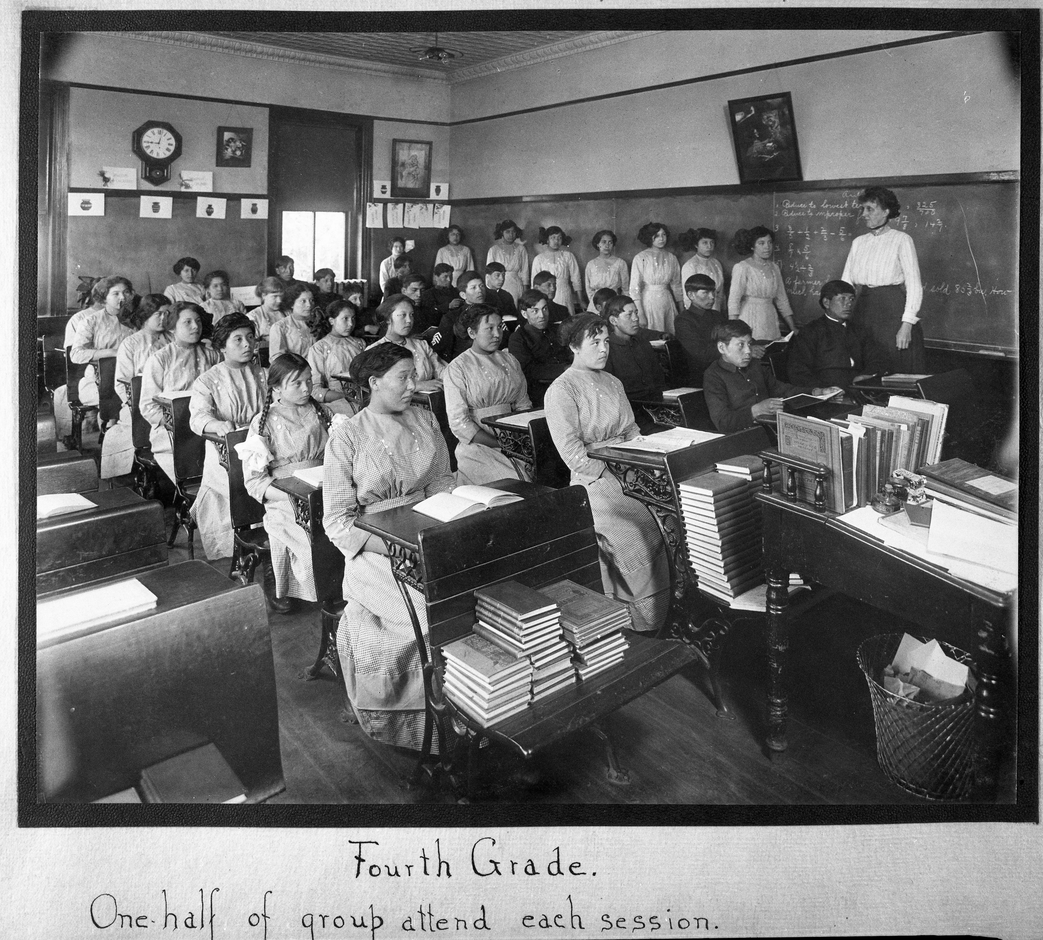 In this undated photo provided by National Archives, fourth grade students sit in a classroom at the former Genoa Indian Industrial School in Genoa, Nebraska. Researchers are now trying to locate the bodies of more than 80 Native American children buried near the school in central Nebraska. For decades, the location of the student cemetery has been a mystery, lost over time after the school closed in 1931 and memories faded of the once-busy campus that sprawled over 640 acres in the tiny community of Genoa.