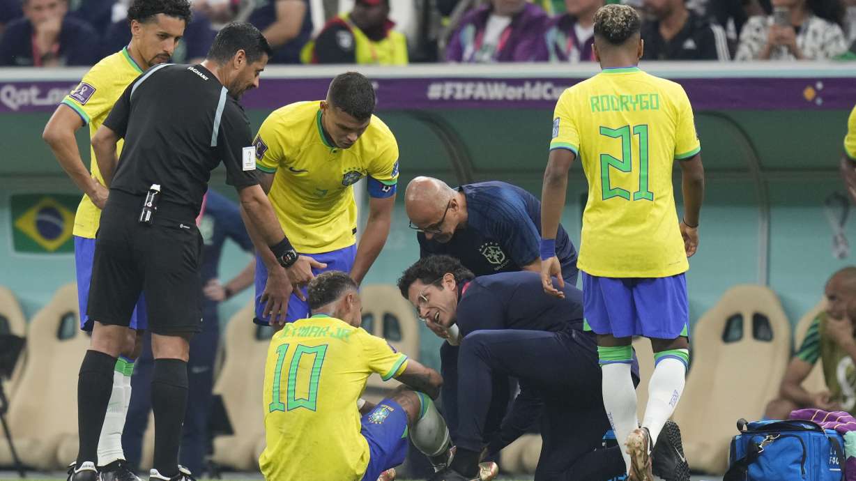 Brazil's Neymar, bottom, is treated by members of his team during the World Cup group G soccer match between Brazil and Serbia, at the Lusail Stadium in Lusail, Qatar, Thursday, Nov. 24, 2022.