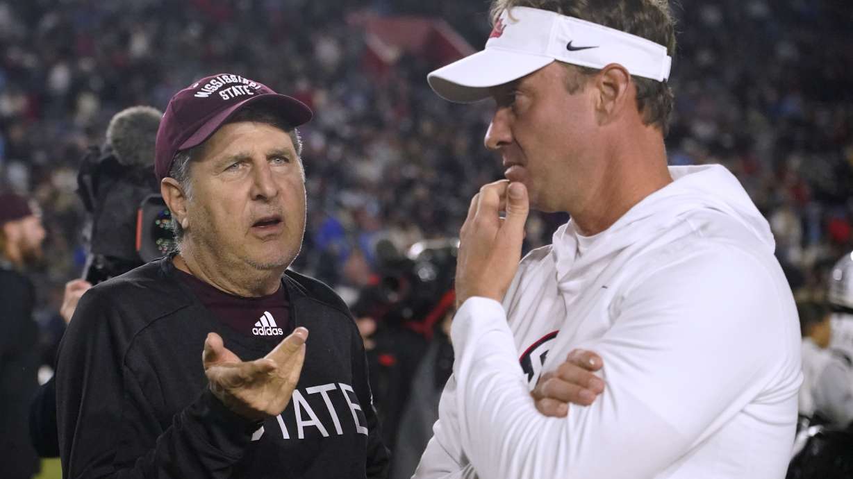 Mississippi State coach Mike Leach, left, talks with Mississippi coach Lane Kiffin before an NCAA college football game in Oxford, Miss., Thursday, Nov. 24, 2022.