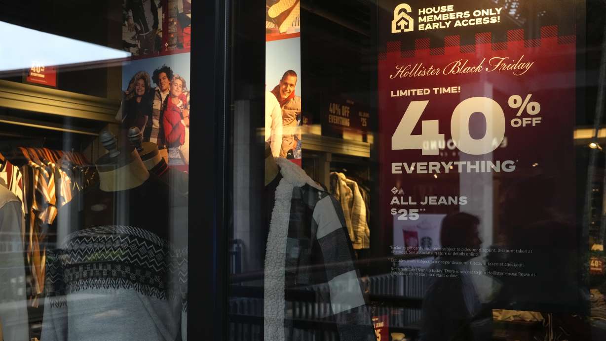 The reflections of passing shoppers are seen in the glass of a Hollister clothing store advertising sales, ahead of Black Friday and the Thanksgiving holiday, Monday in Miami. Retailers are ushering in the start of the holiday shopping season on the day after Thanksgiving, preparing for the biggest crowds since 2019.