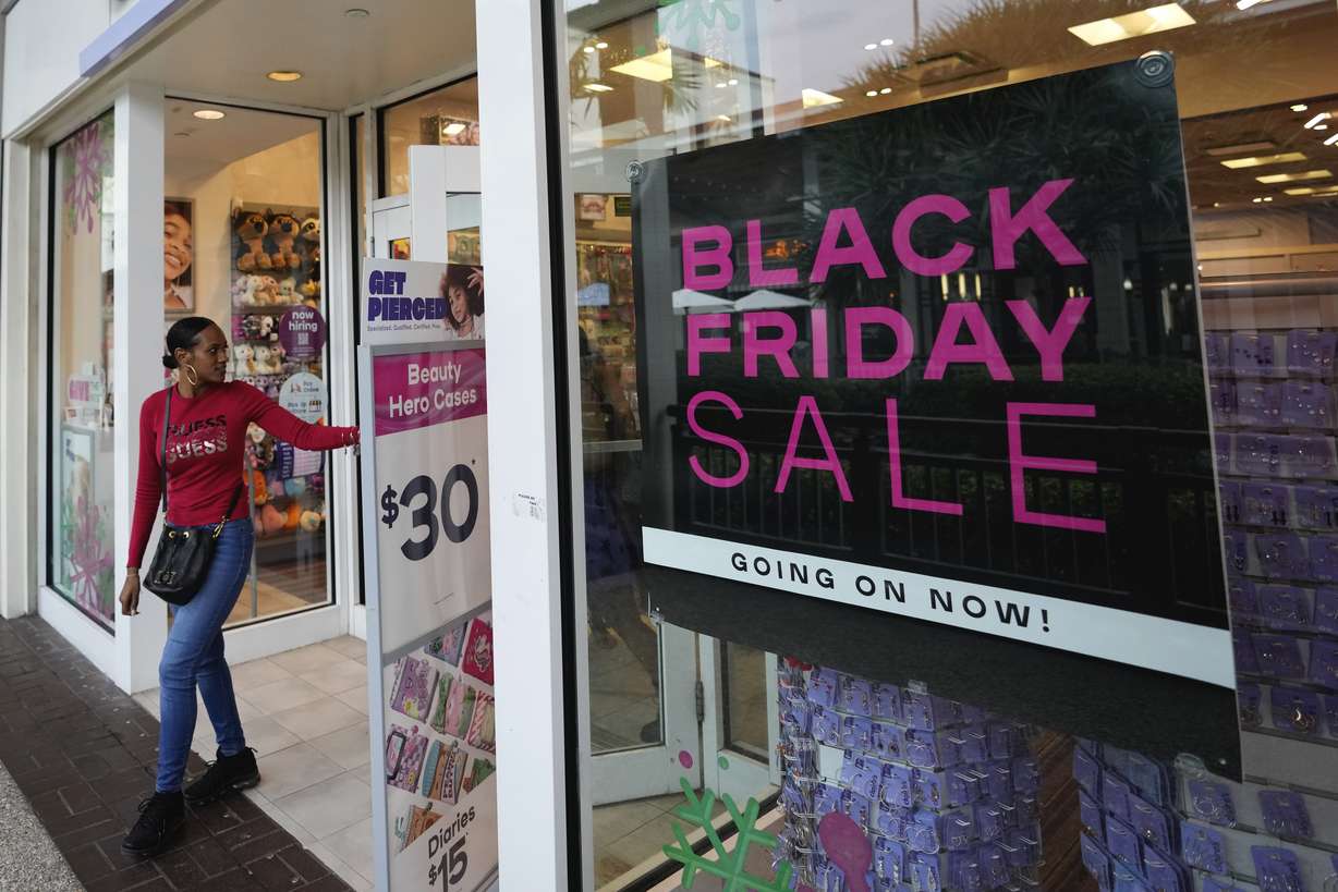 Shoppers exit a Claire's accessories store advertising sales ahead of Black Friday and the Thanksgiving holiday, Monday, Nov. 21, in Miami. Retailers are ushering in the start of the holiday shopping season on the day after Thanksgiving, preparing for the biggest crowds since 2019.