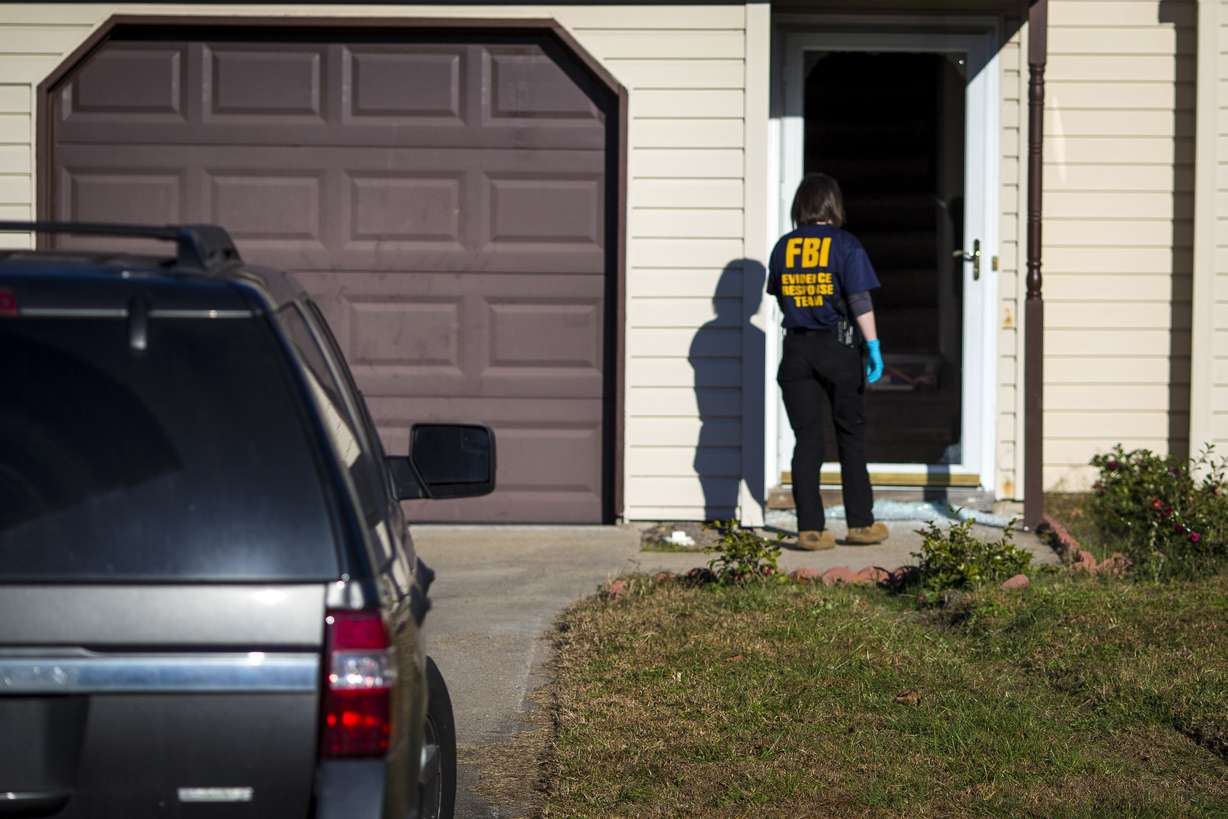 An FBI agent enters the home of Andre Bing, Wednesday, Nov. 23, in Chesapeake, Va. Bing, a Walmart manager, opened fire on fellow employees in the break room of a Virginia store, killing six people.