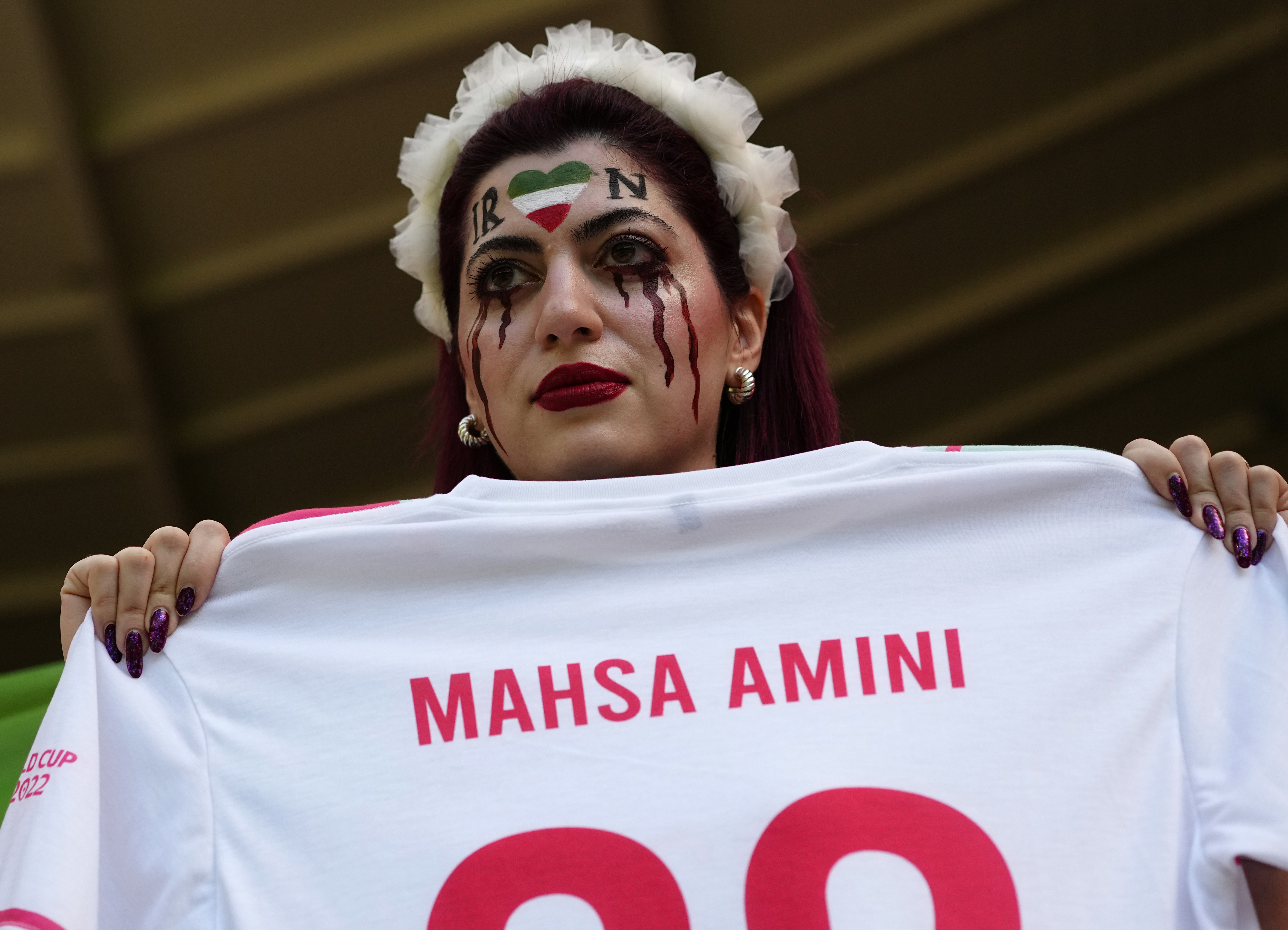 A woman holds a jersey with the name of Mahsa Amini, a woman who died while in police custody in Iran at the age of 22, as she takes her place in the stands ahead of the World Cup group B soccer match between Wales and Iran, at the Ahmad Bin Ali Stadium in Al Rayyan, Qatar, Friday, Nov. 25, 2022. 