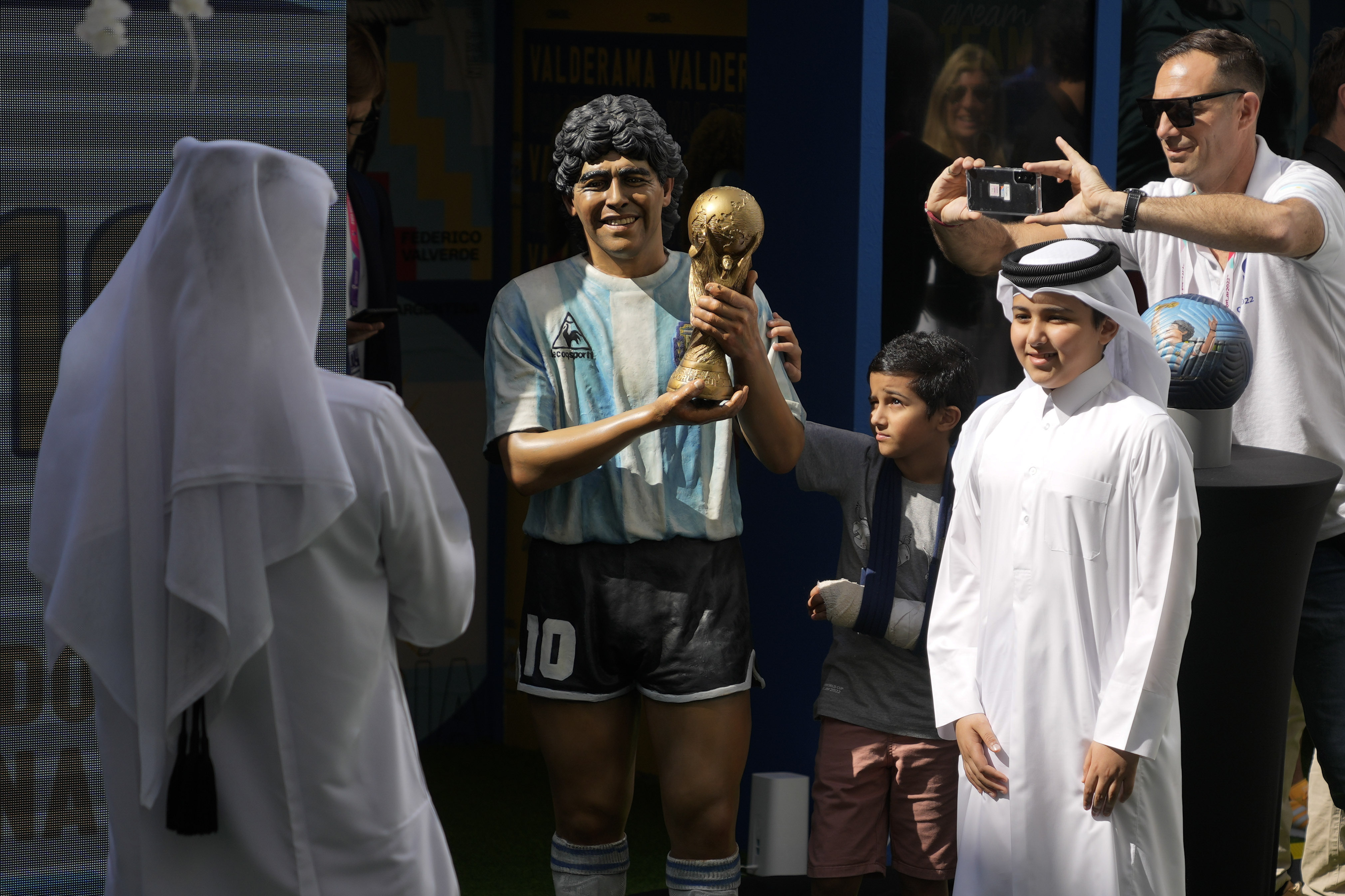 Children pose for a picture with a statue of the late soccer star Diego Maradona during a commemoration in his honor in Doha, in Friday, Nov. 25, 2022. 