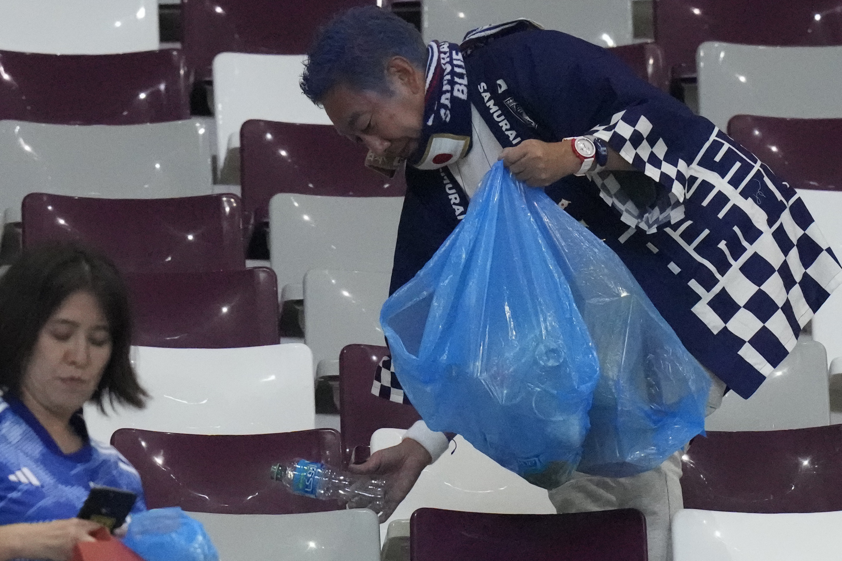 Japan supporters clean the stands at the end of the World Cup group E soccer match between Germany and Japan, at the Khalifa International Stadium in Doha, Qatar, Wednesday, Nov. 23, 2022. Japan won 2-1.
