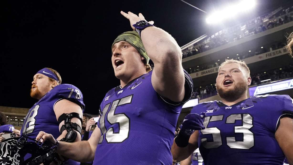 TCU quarterback Max Duggan (15) reacts on the sidelines with teammates guards John Lanz (53) and Wes Harris during the second half of an NCAA college football game against Iowa State in Fort Worth, Texas, Saturday, Nov. 26, 2022. TCU won 62-14.